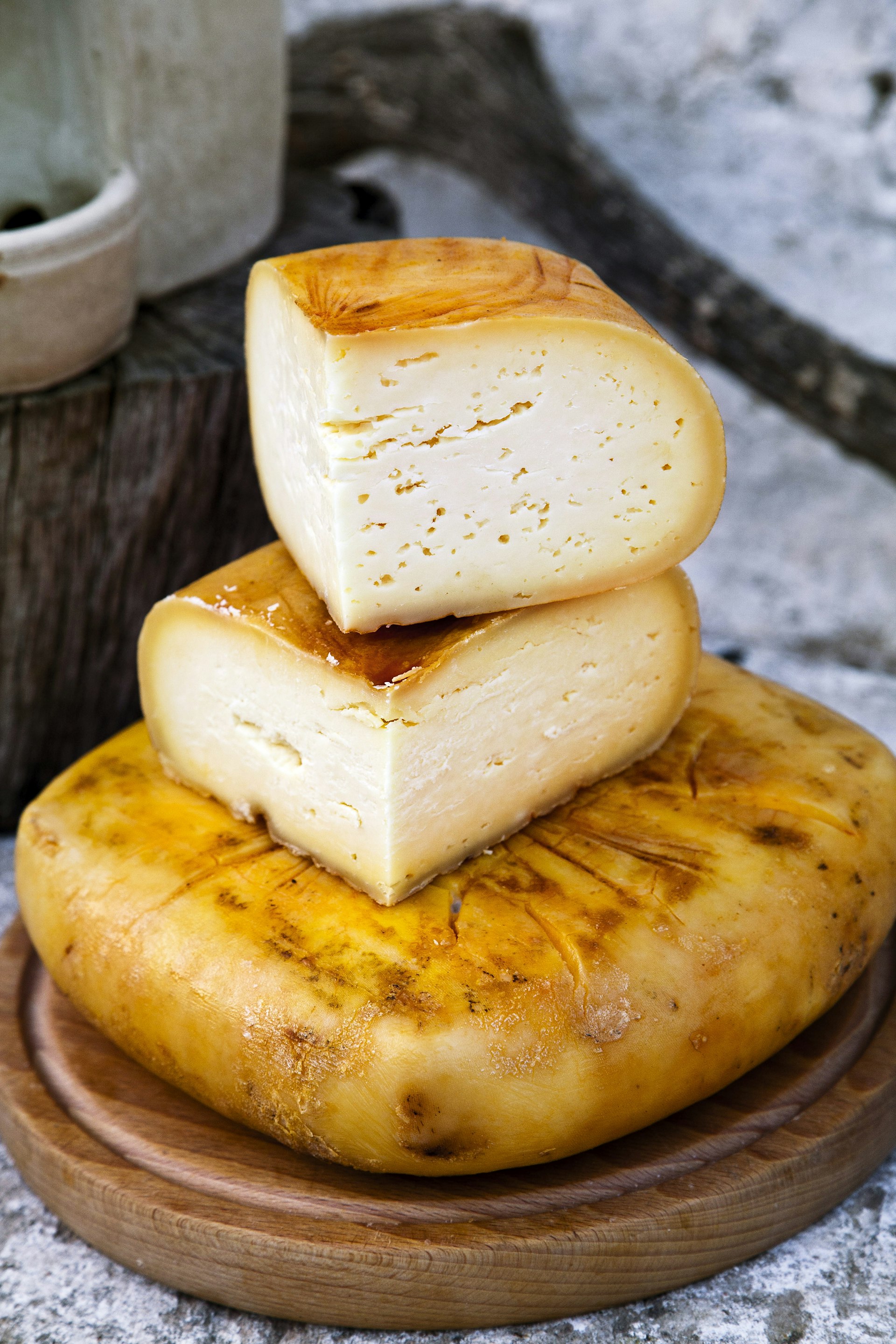 A stack of large round yellow-white cheeses on a wooden board