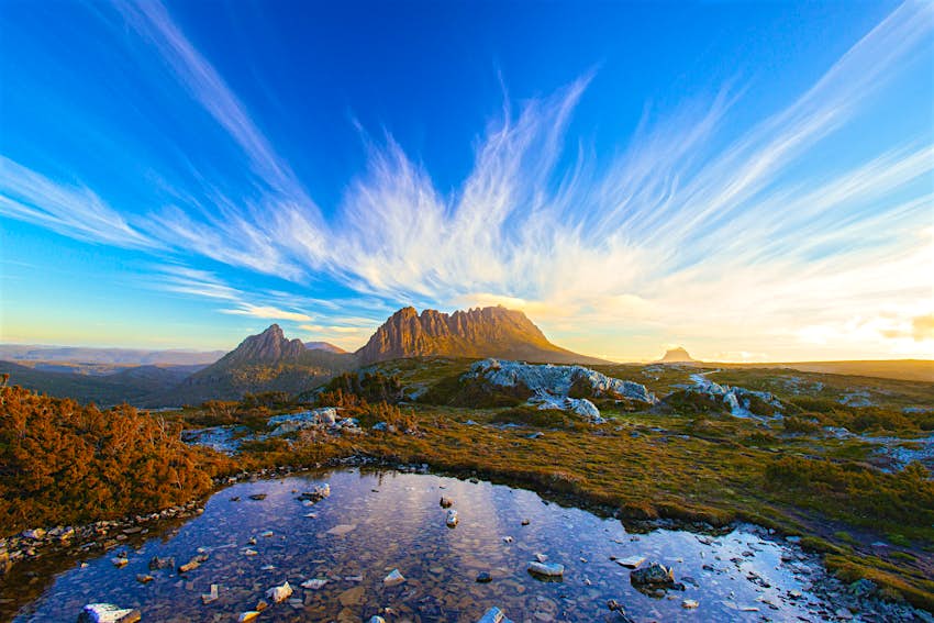 Panoramic view of the Cradle Mountain with bright blue skies and lush green forests  