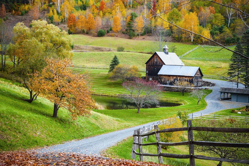Fall foliage, New England countryside at Woodstock, Vermont, farm in autumn landscape. Old wooden barn surrounded by colorful trees.