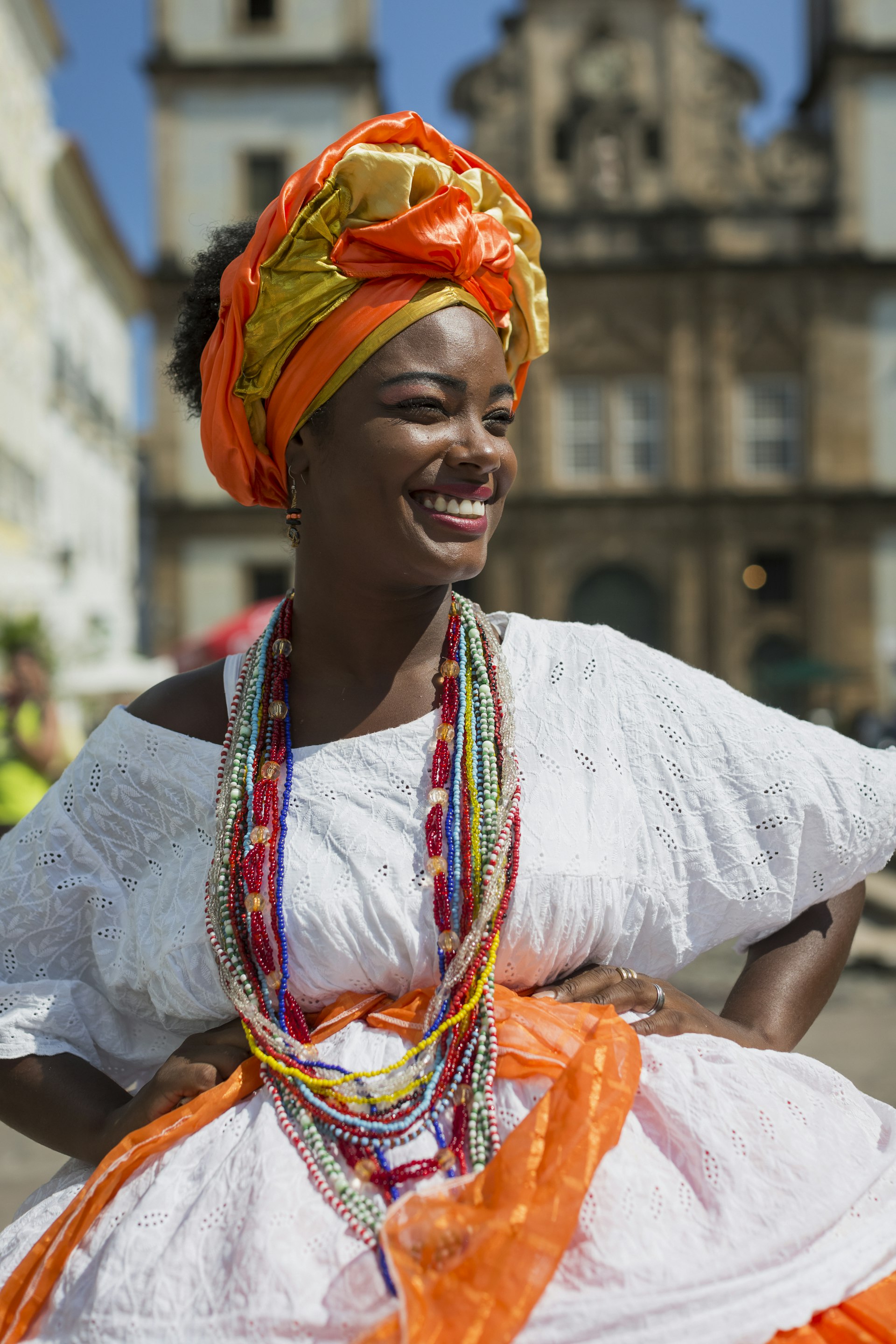 A woman wears typical Afro-Baiana dress in Salvador, Bahía, with a colonial-era church in the background