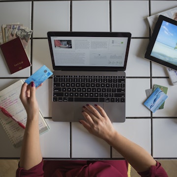 Young woman using a laptop to work out her travel itinerary and pay with her credit card.