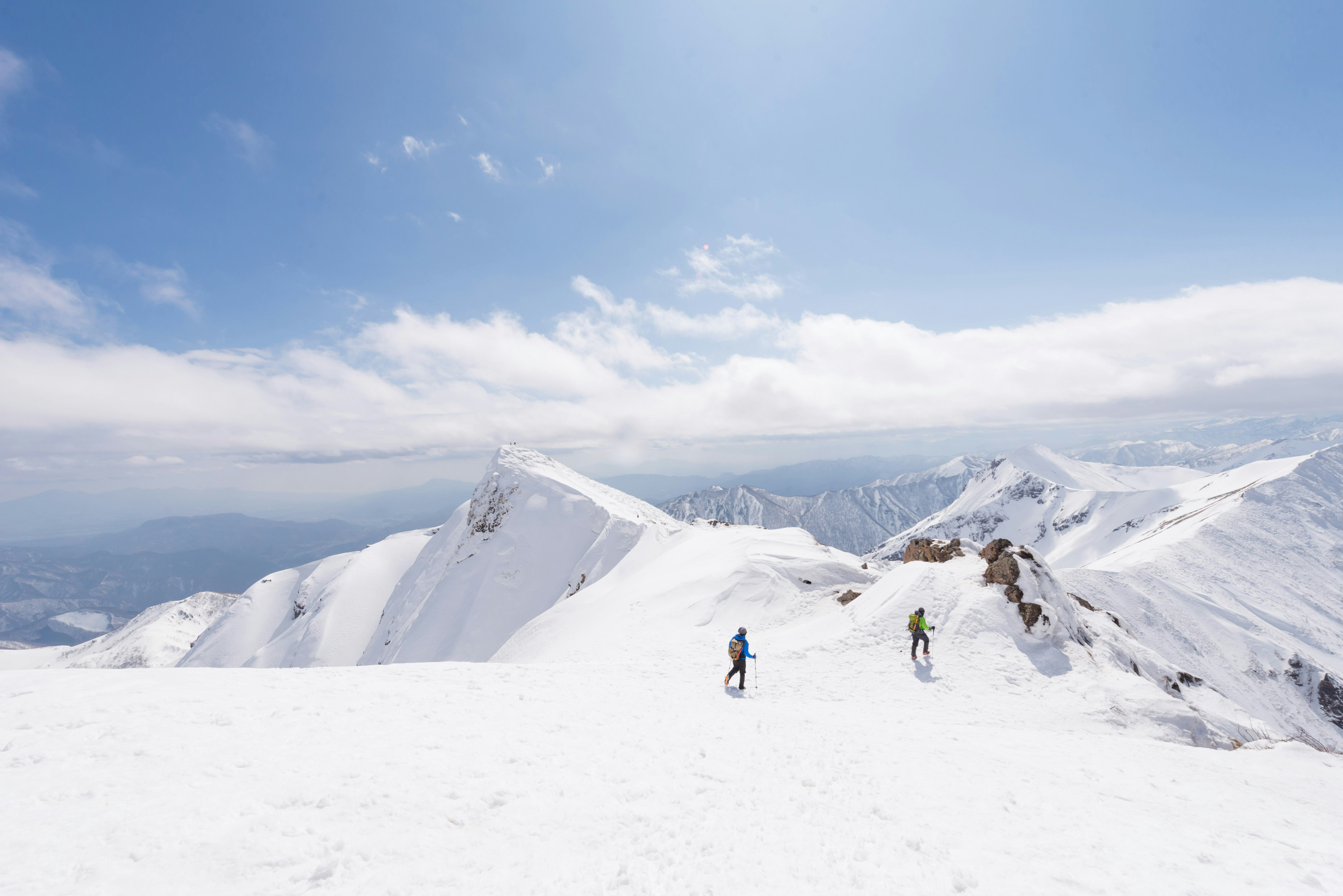 People look tiny against the huge expanse of a snow-covered mountain in Japan