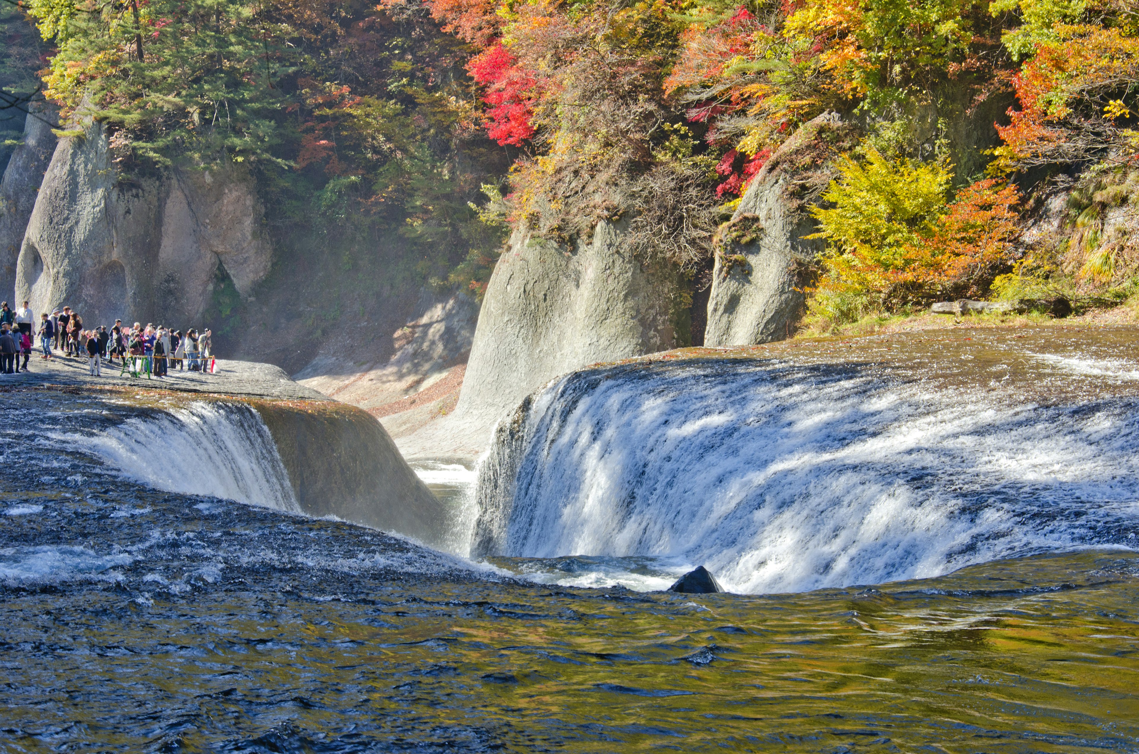 Water slams through the narrow horseshoe of a waterfall in Japan