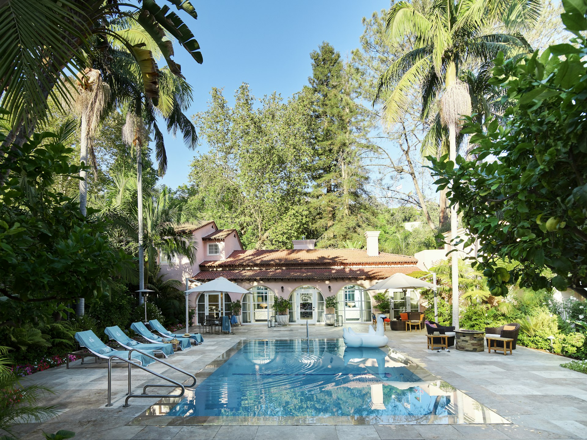 A rectangular pool set outside a pastel-pink villa 
