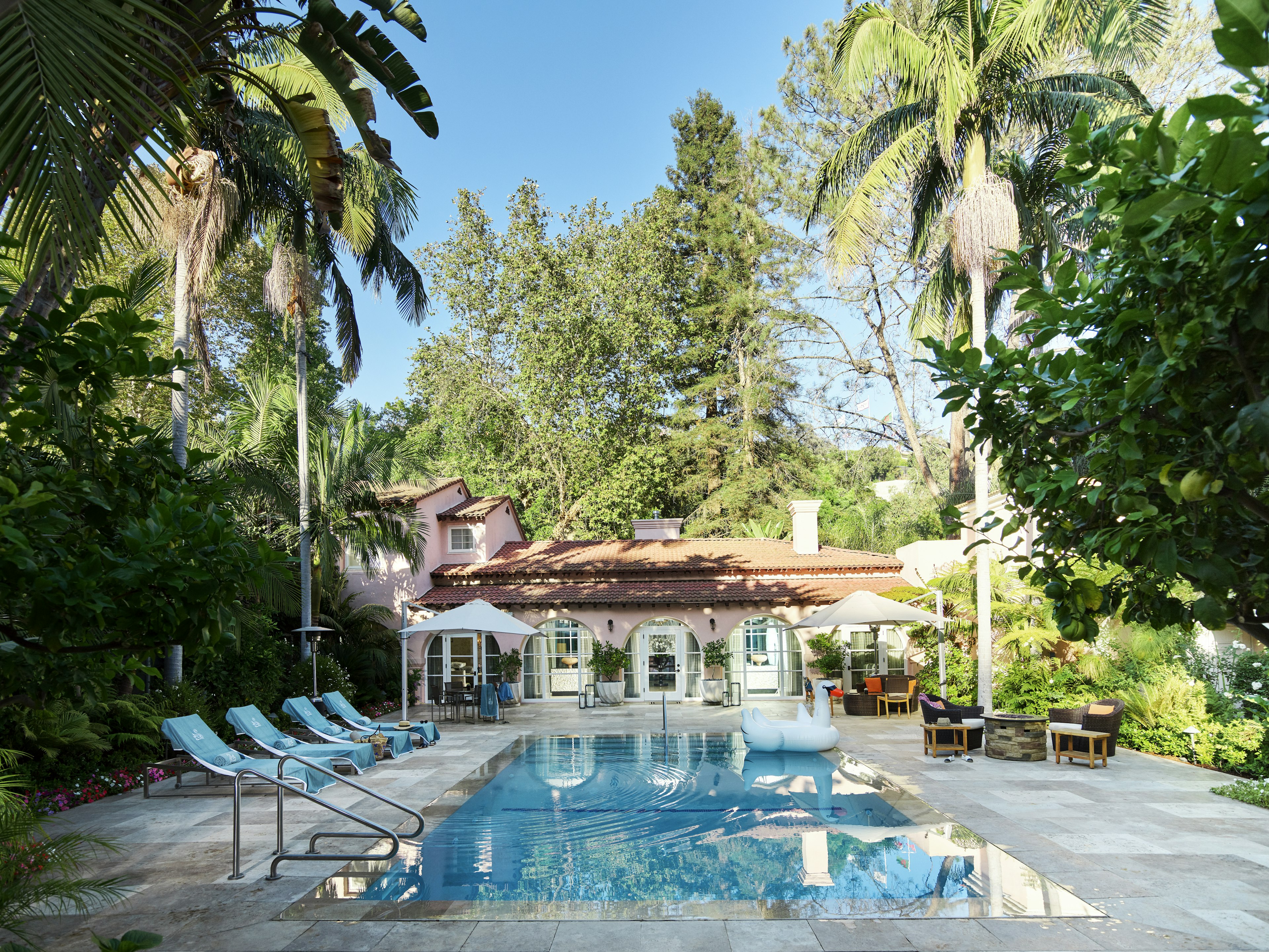 A rectangular pool set outside a pastel-pink villa