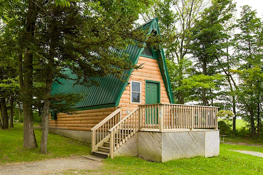 A cream-colored cabin with a green roof at Jellystone Park in Western New York