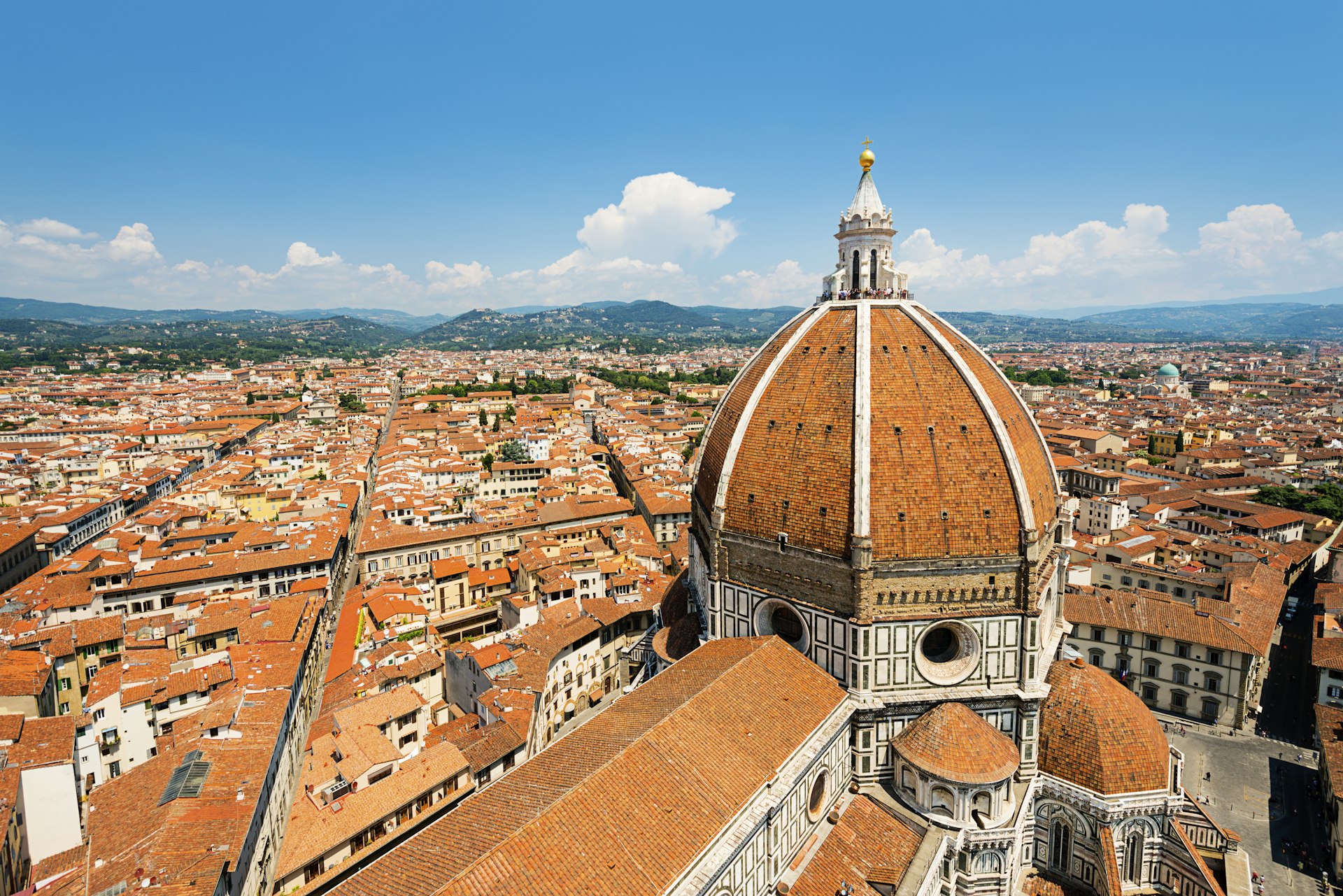 An aerial shot of the famous red tiled dome of Florence's Duomo, which stands tall above a sea of other red-tiled roofs