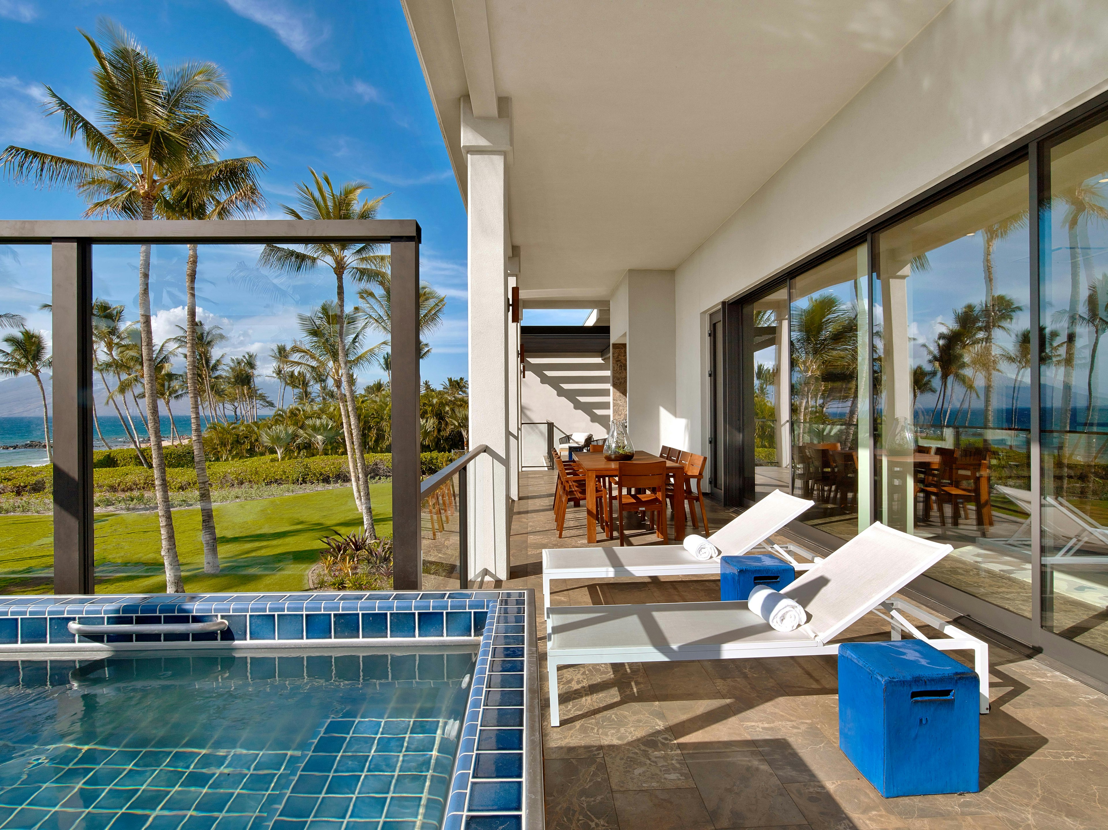 Two sunloungers stand next to a pool in a private villa