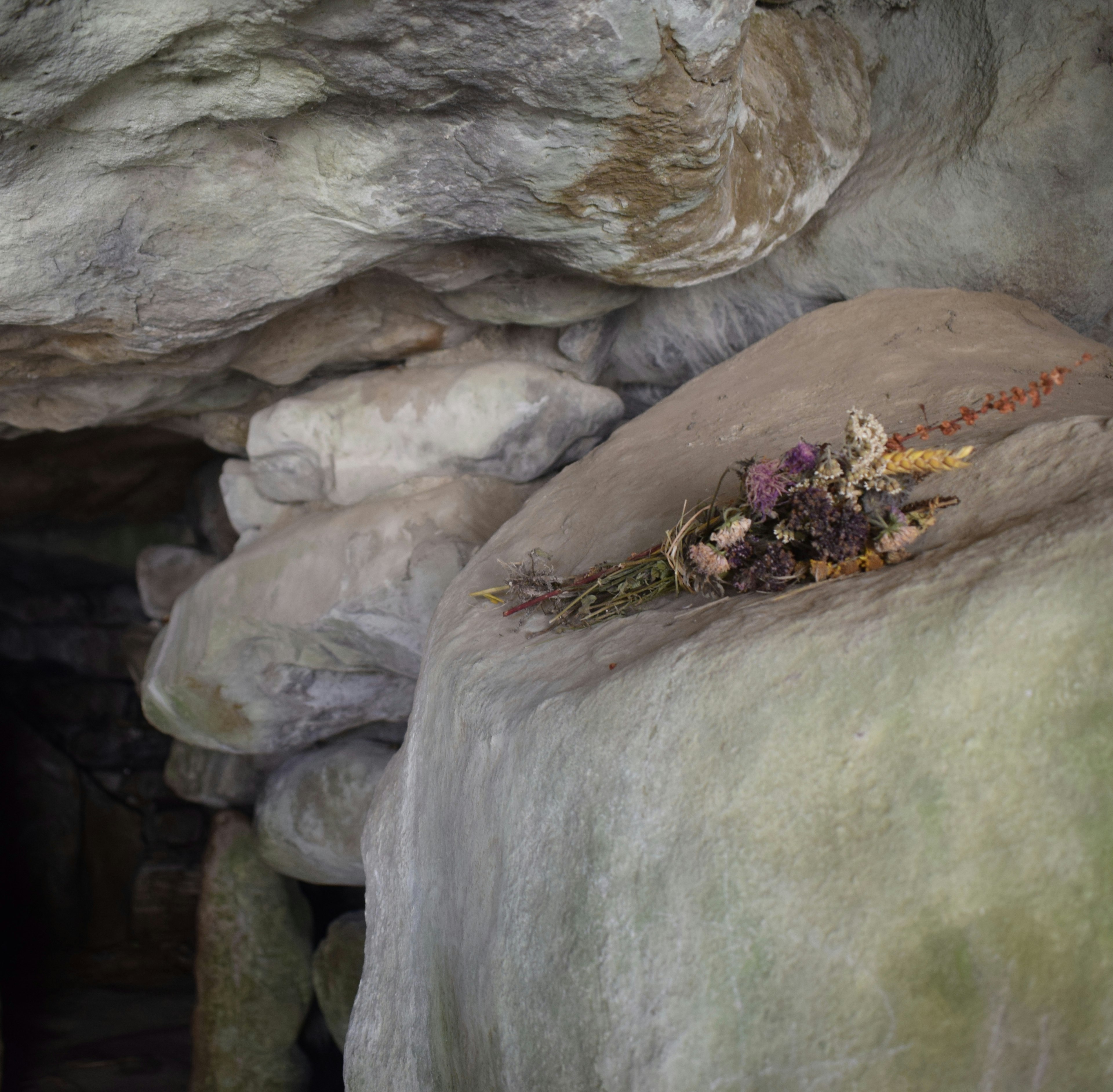 A bundle of dried herbs tied together and placed as an offering on a stone within a pagan site