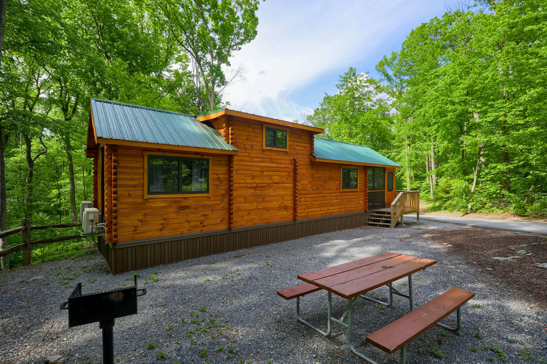 A cabin in a gravel lot with a grill at Yogi Bear's Jellystone Park Camp-Resort: Quarryville