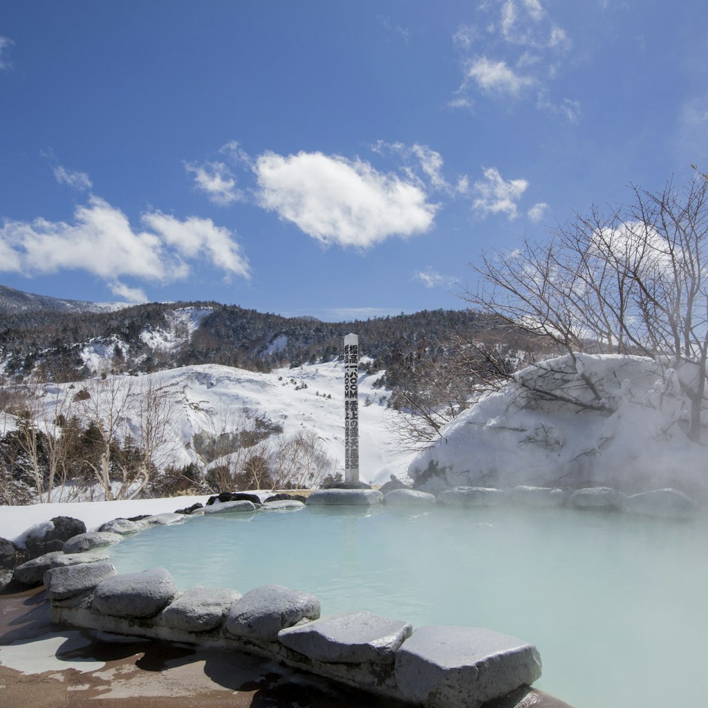 Snowy hills frame the steamy hot springs at Manza Onsen in Japan's Gunma Prefecture