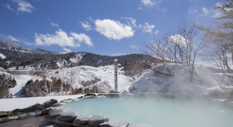 Snowy hills frame the steamy hot springs at Manza Onsen in Japan's Gunma Prefecture