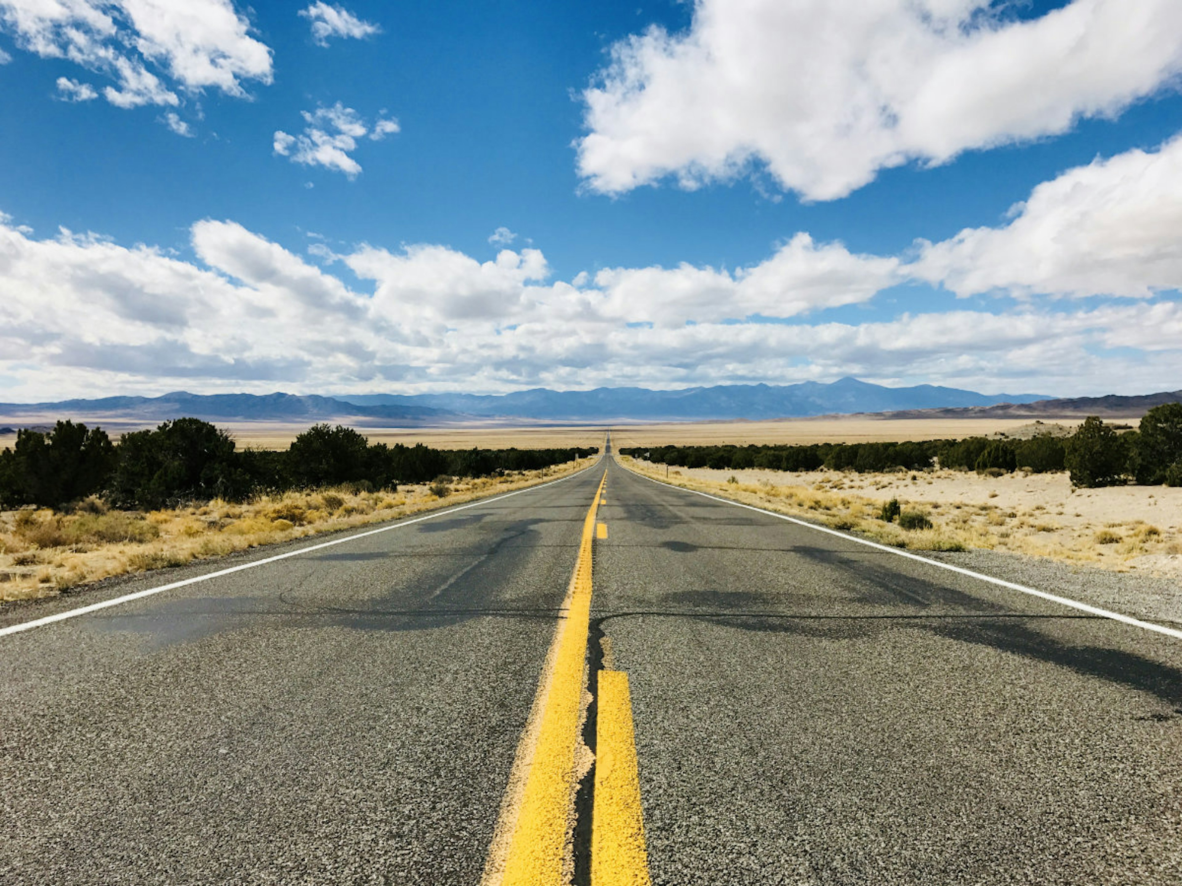 An open two-lane highway stretching into the distance with no vehicles on it