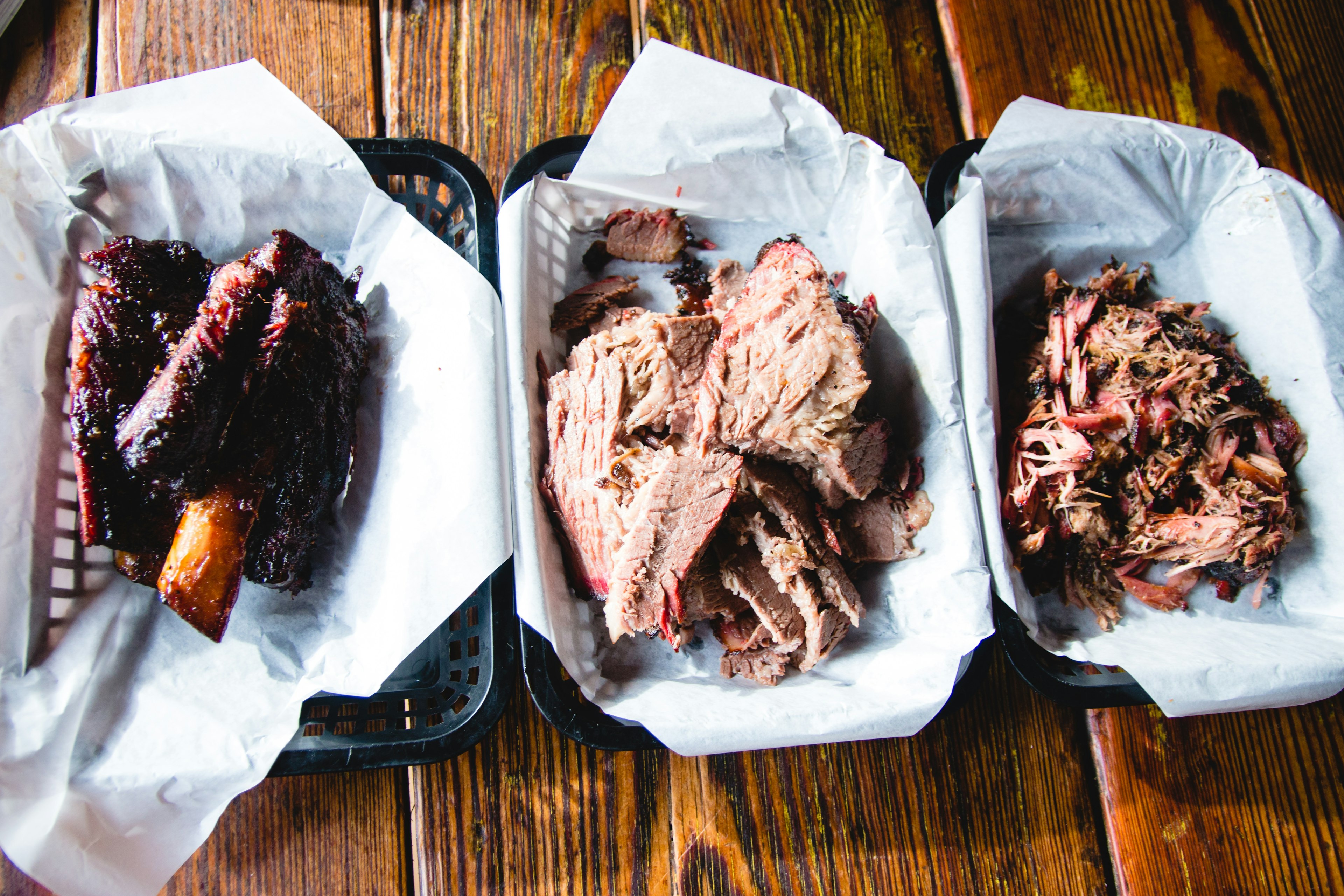 Ribs, brisket and pulled pork on a wooden table