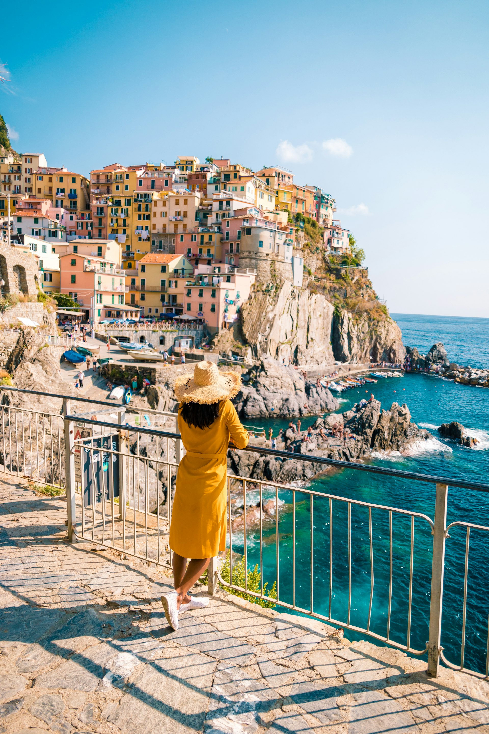 A woman stands in front of the beautiful village of Cinque Terre. 