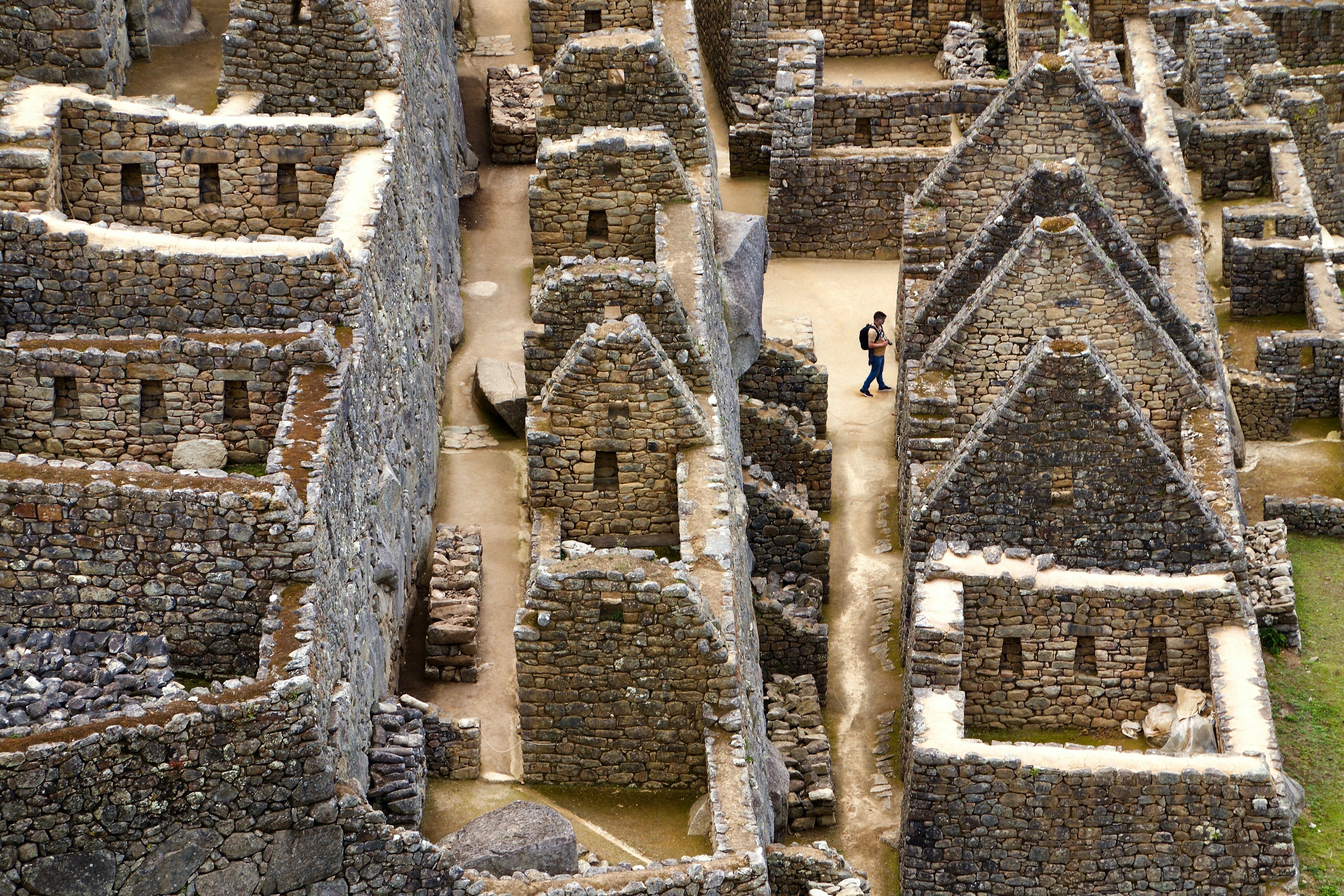 An aerial picture of a man wandering through stone ruins.