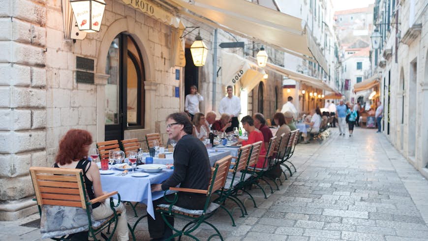 People eat at a patio restaurant nestled in a historic alleyway in Dubrovnik