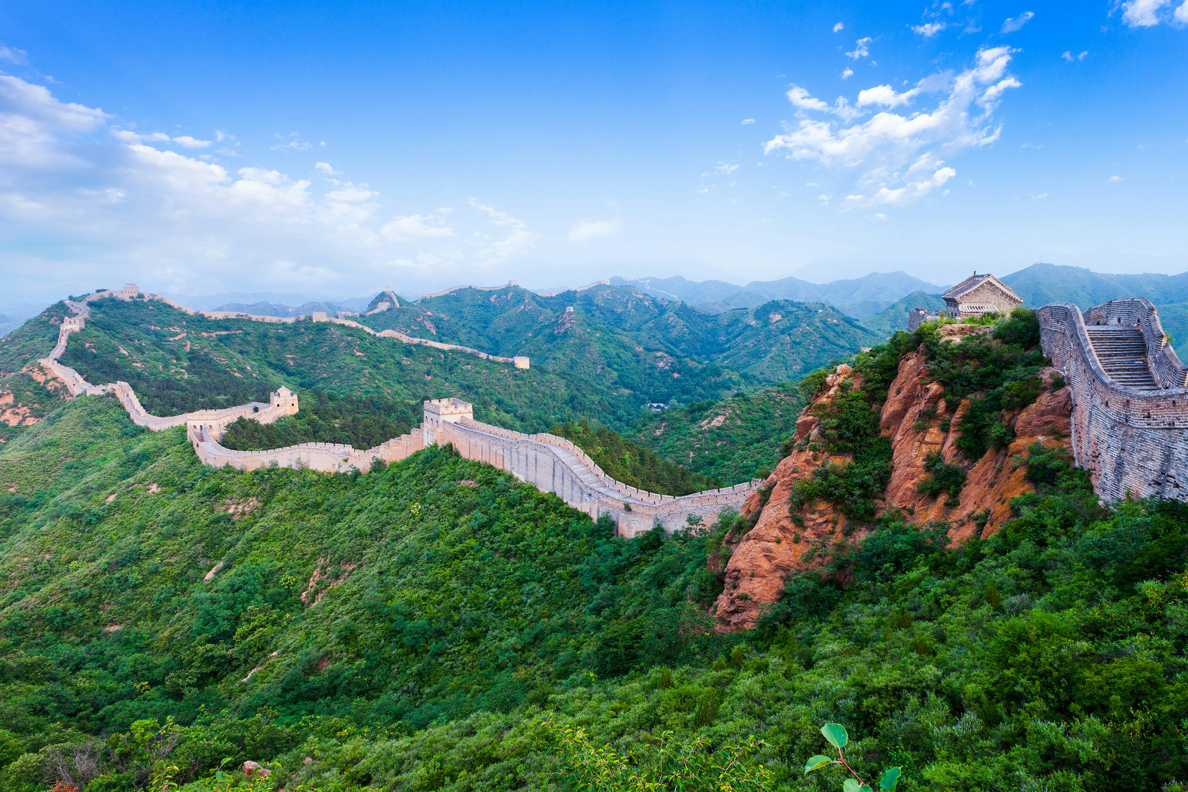 A stretch of the Great Wall with green mountains in the background.