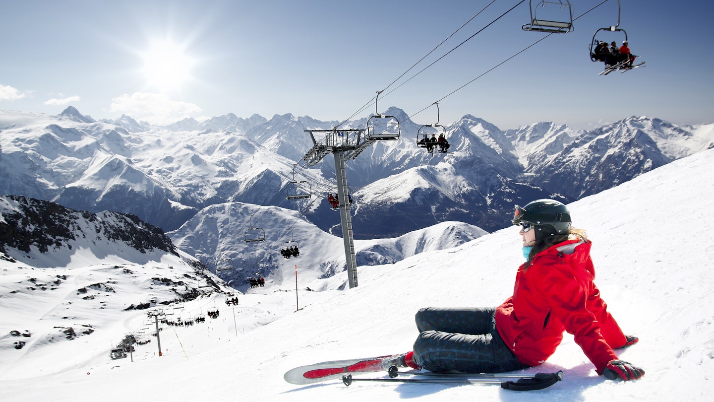 Girl skier lying on snow with ski, French Alps High mountain