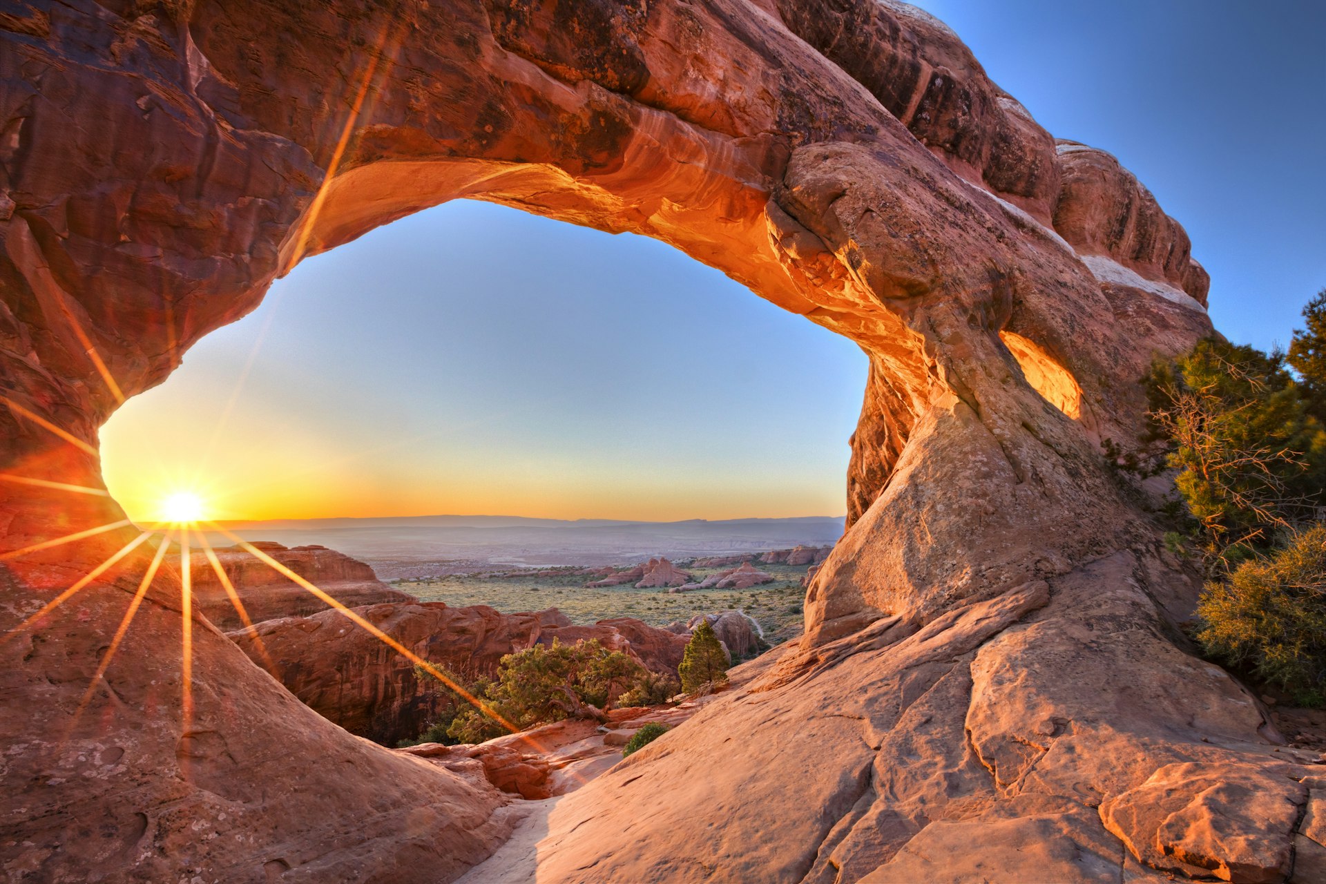 A natural stone archway with the sun in the background