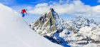 Skier skiing downhill in high mountains in fresh powder snow. Snow mountain range with Matterhorn in background. Zermatt Alps region Switzerland.