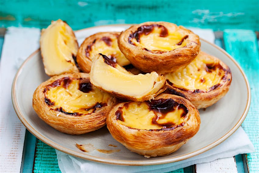 Egg tarts known as pastel de nata in Portugal are stacked on a plate