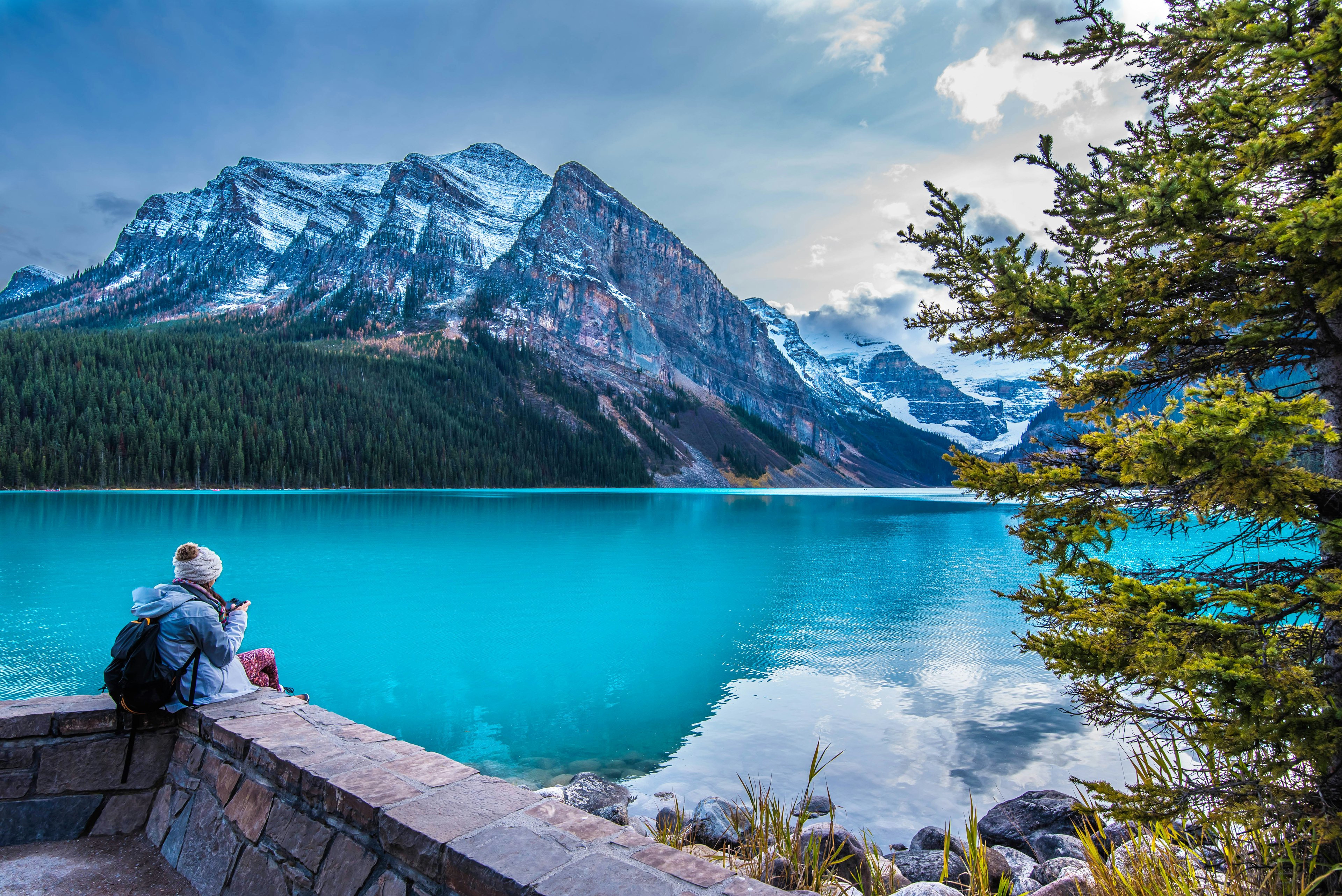 A girl sits on the shore of Lake Louise in Banff National Park in the Rocky Mountains