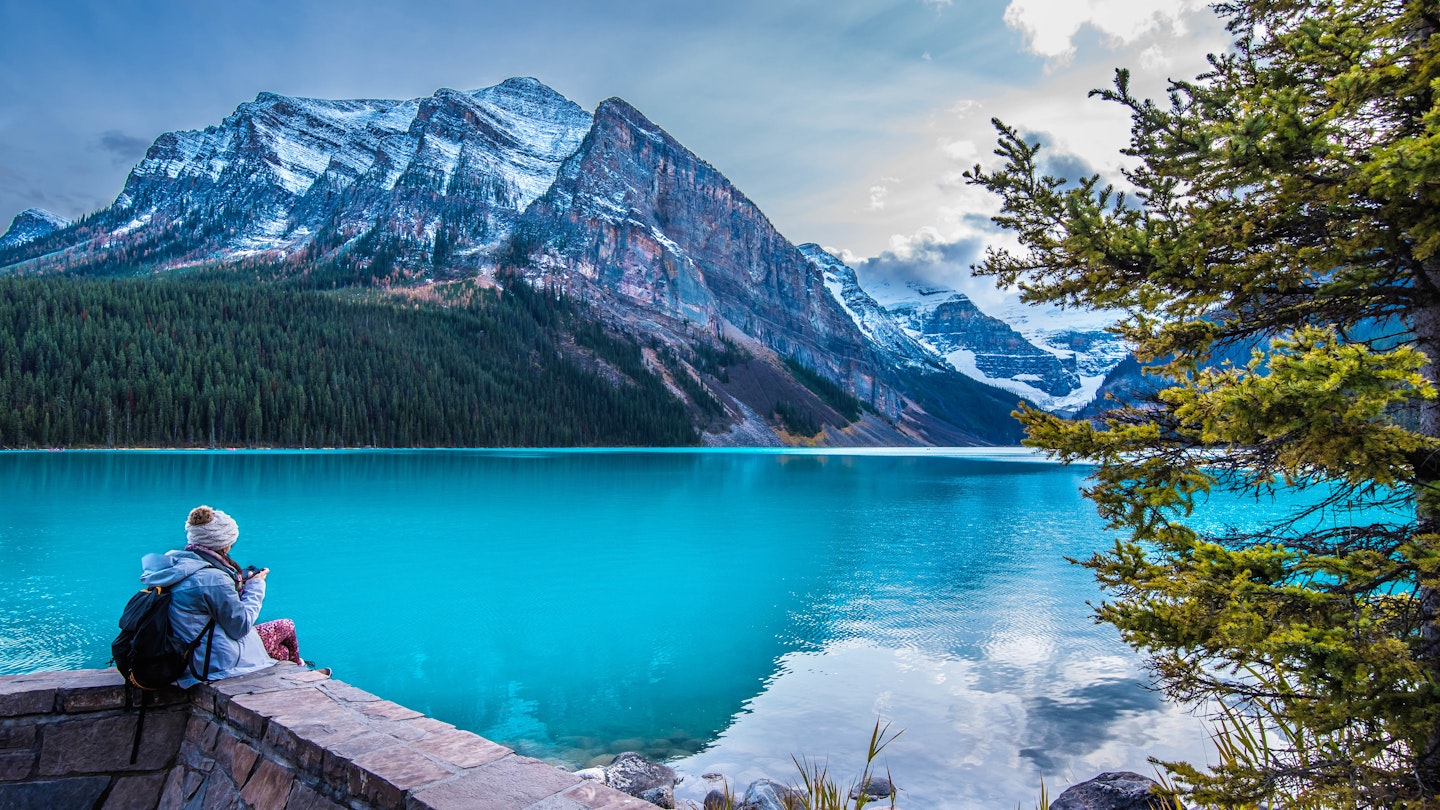 A girl sits on the shore of Lake Louise in Banff National Park in the Rocky Mountains.
