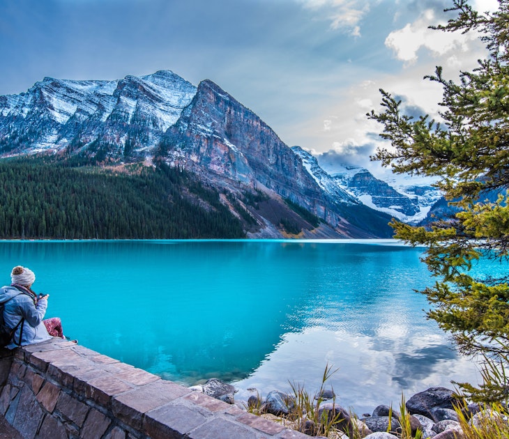 A girl sits on the shore of Lake Louise in Banff National Park in the Rocky Mountains.