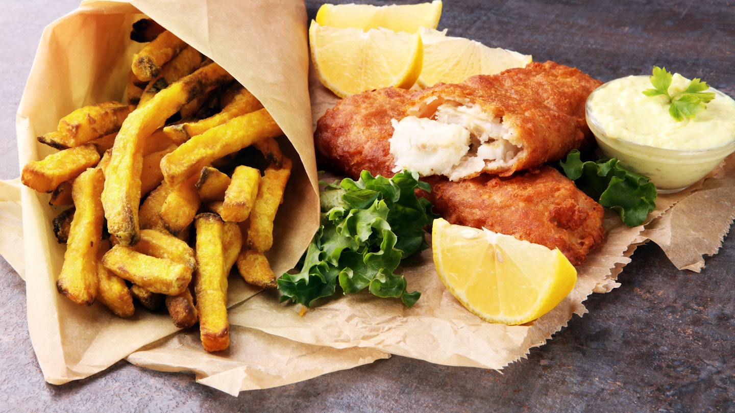 Traditional British style fish and chips on a grey table.
