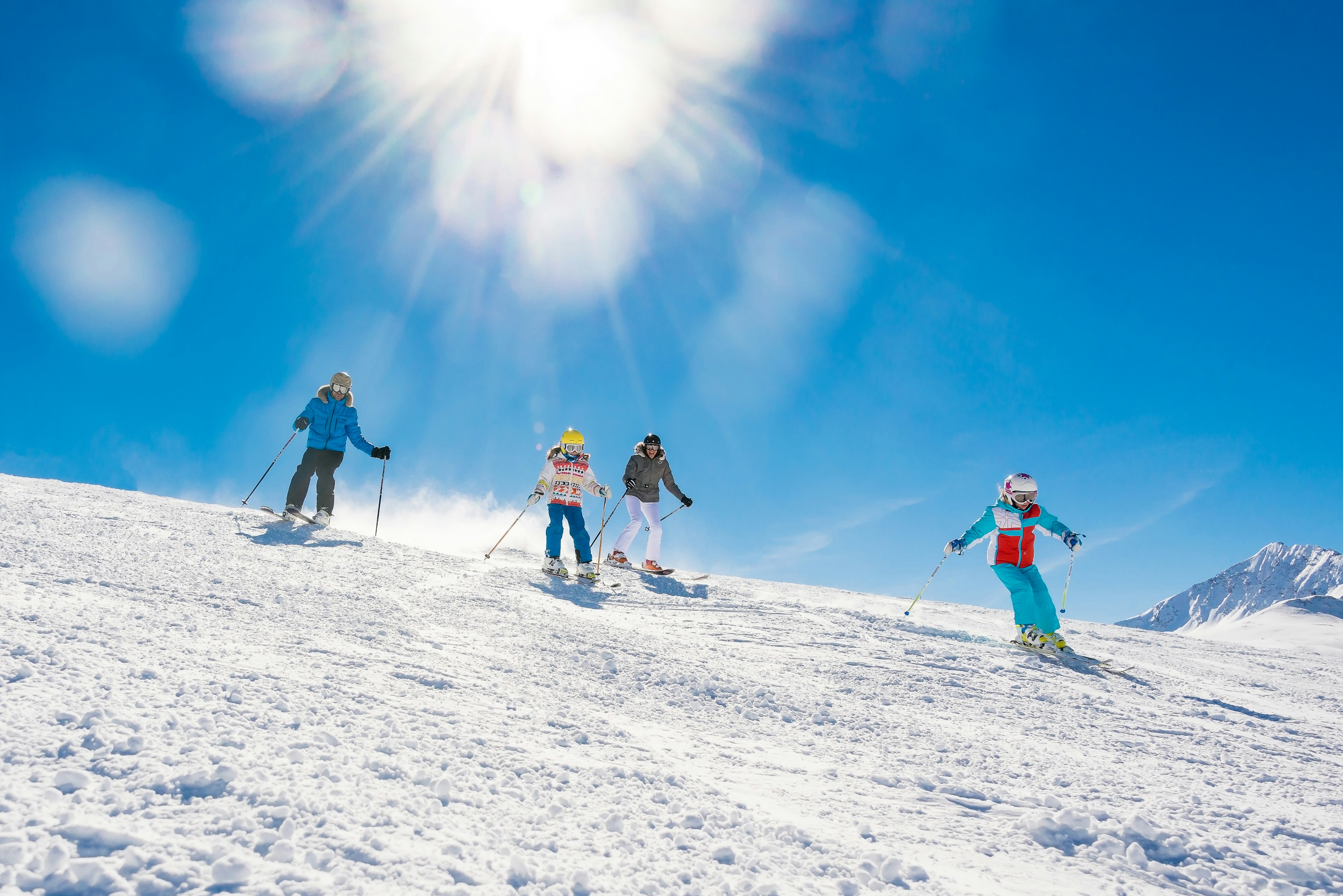 A group of two adults and two children ski down a slope together