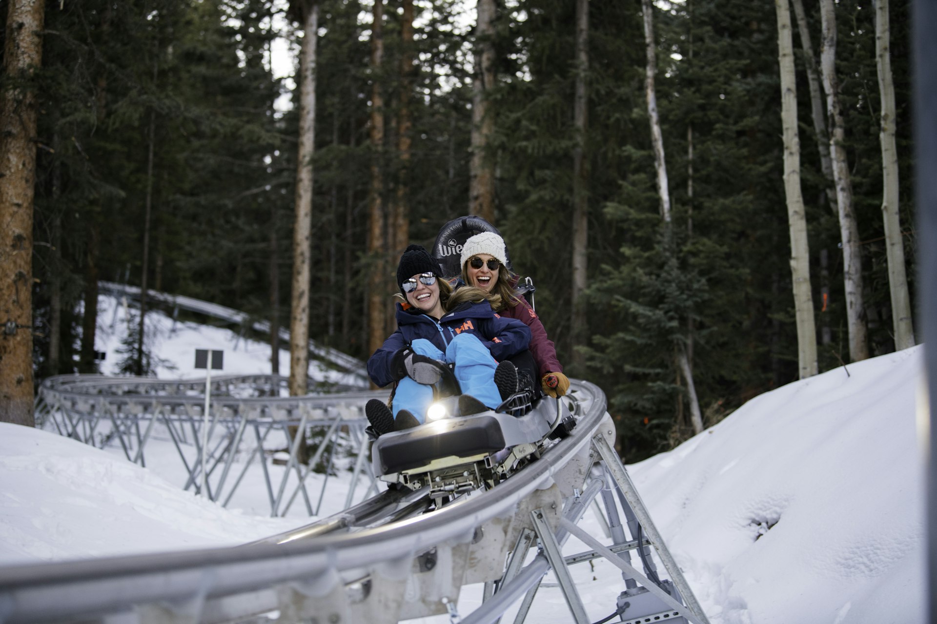 A family rides down a single car on a roller coaster through a snowy landscape