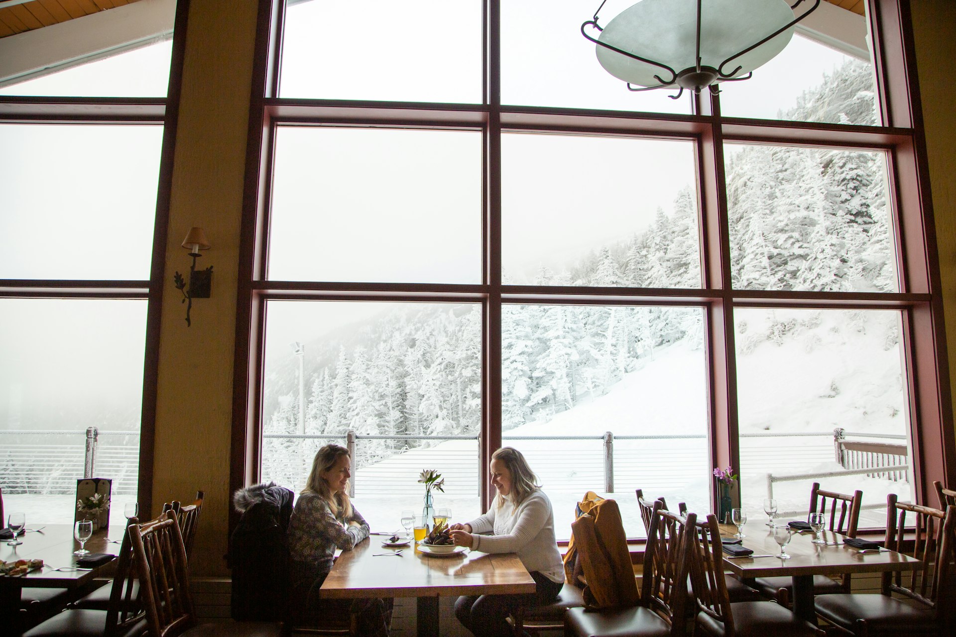Two women eating inside a restaurant with large windows