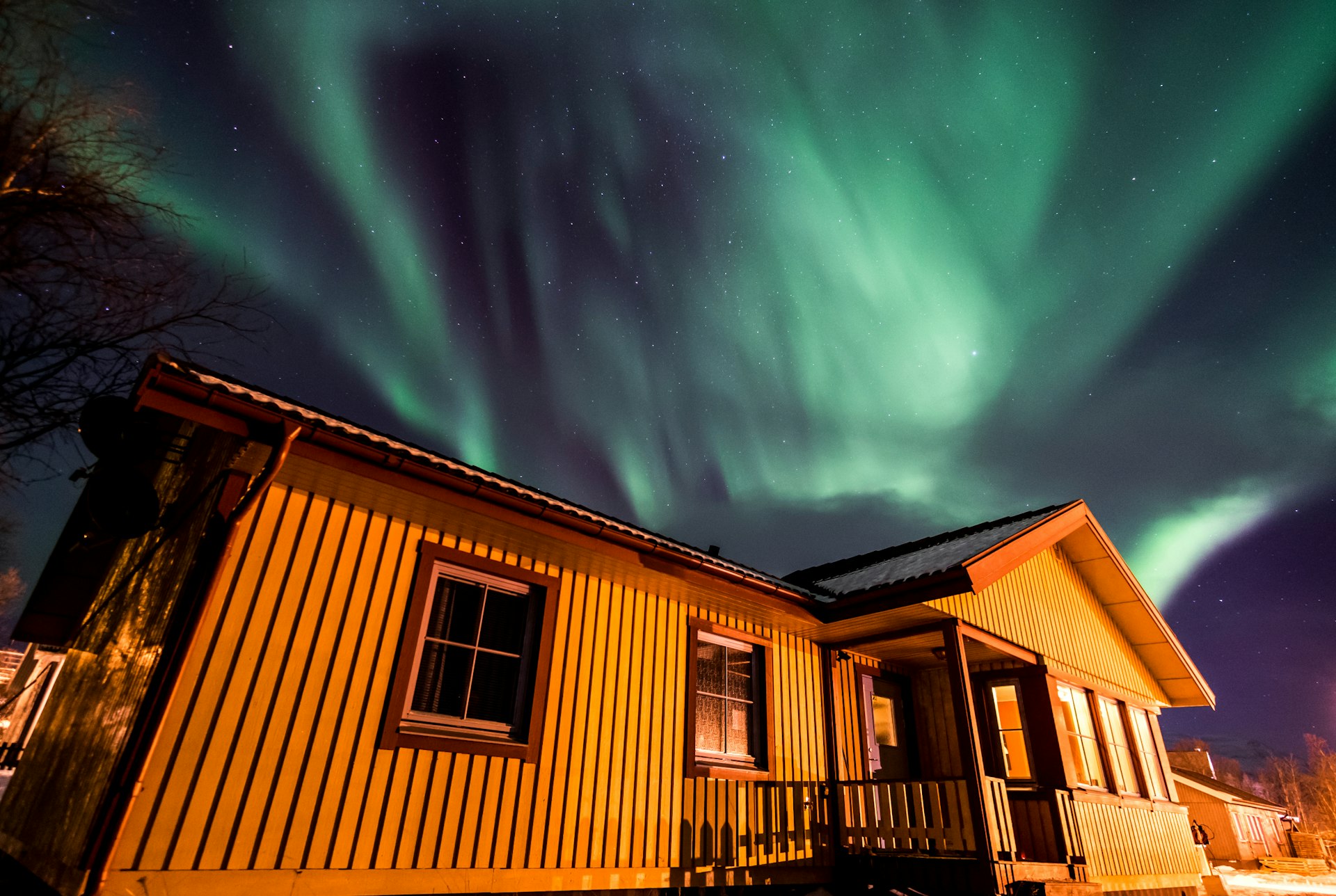 A wooden house with the Northern Lights above it