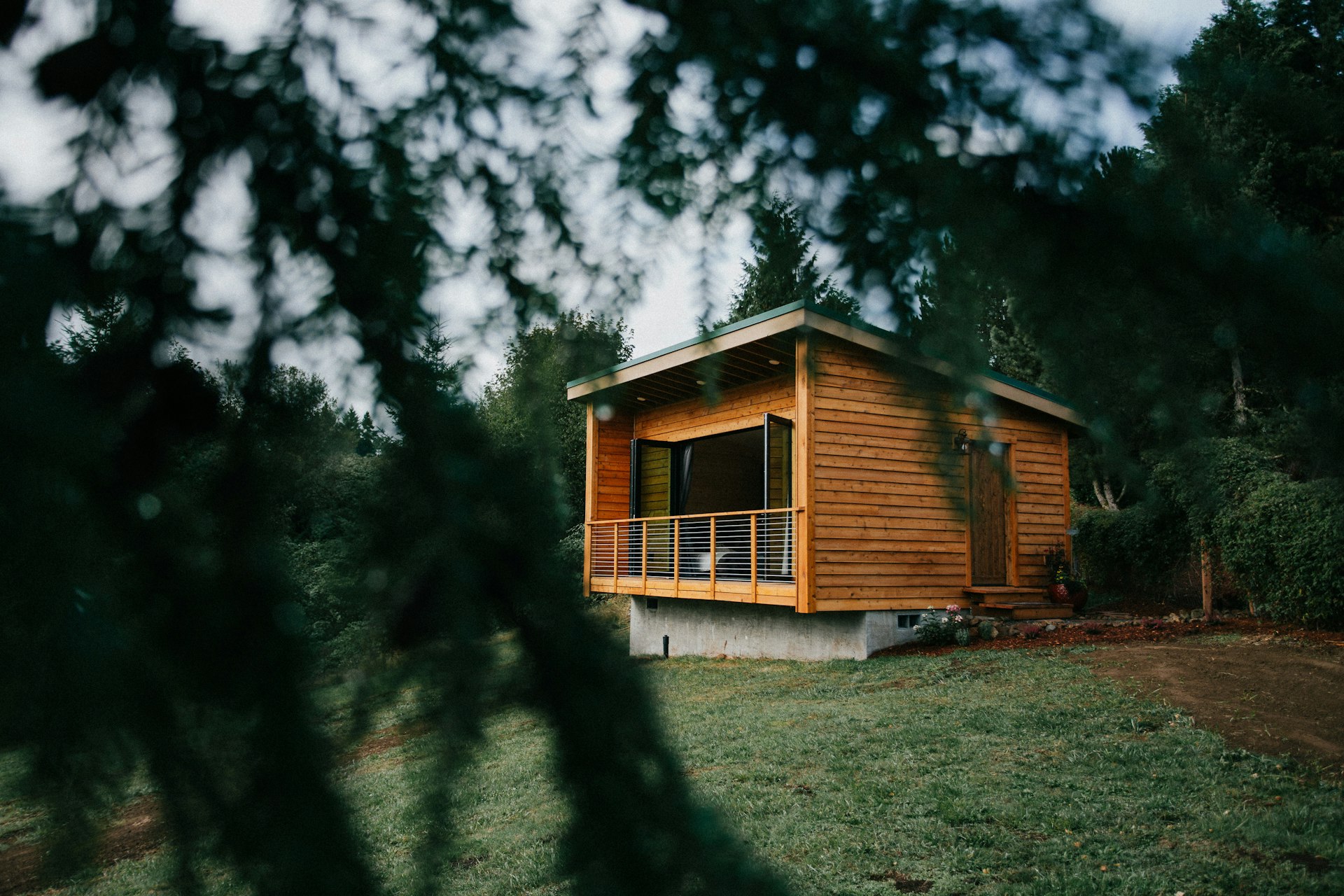 A tiny cedar cabin on a hill in Oregon, seen through tree branches 