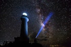 The Milky Way on a clear night with the Uganzaki Lighthouse in the foreground and a laser light shining up into the sky