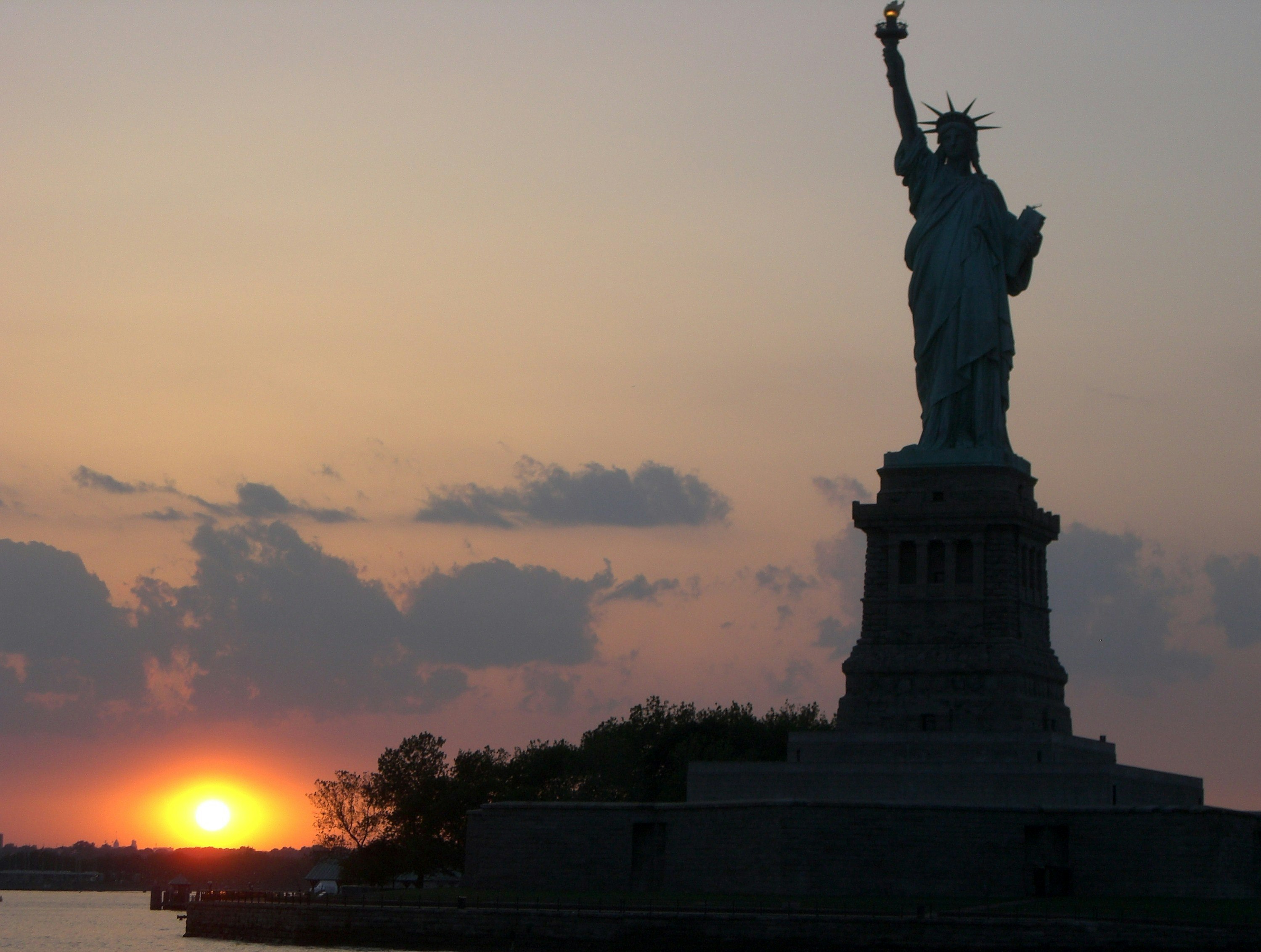 The Statue of Liberty is silhouette as the sun sets in New York.  