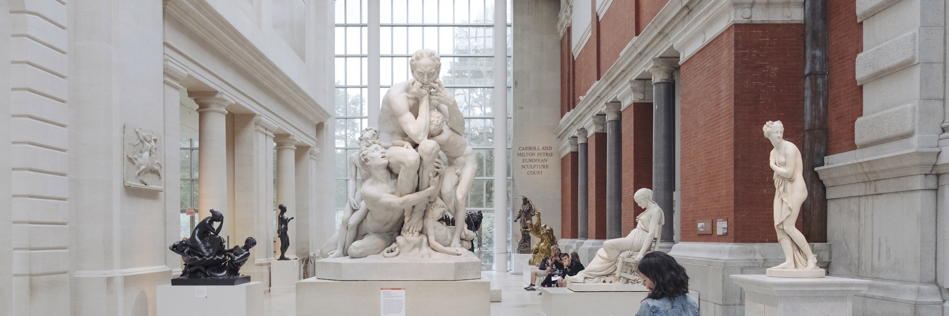 A woman takes notes in front of a sculpture at The Metropolitan Museum of Art.