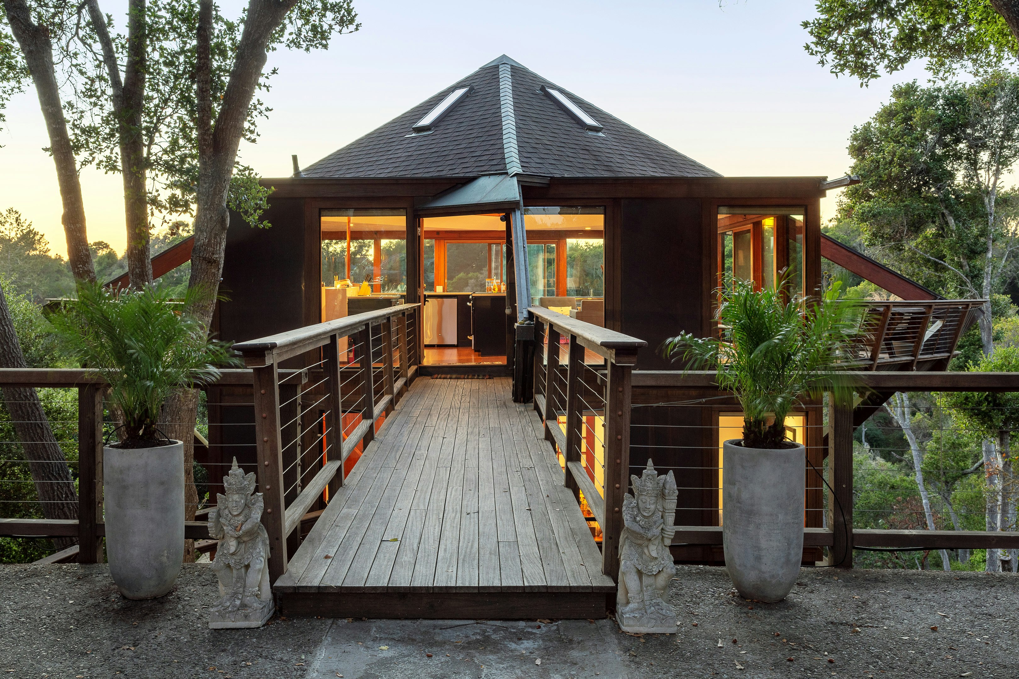 A wooden walkway leads to the entrance of a tree house with an ocean view in Aptos, California