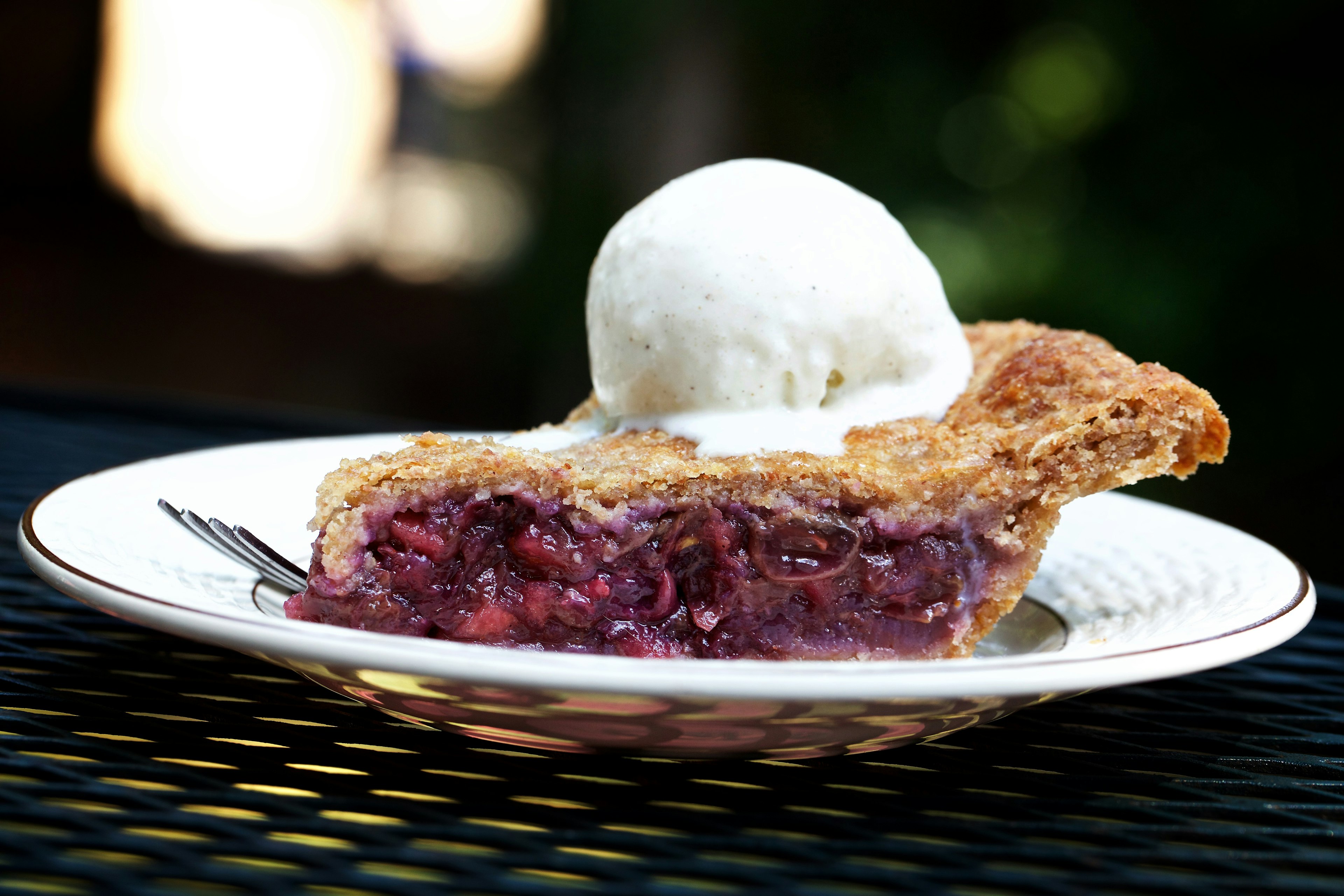 Concord Grape Pie with rye crust is topped with vanilla ice cream