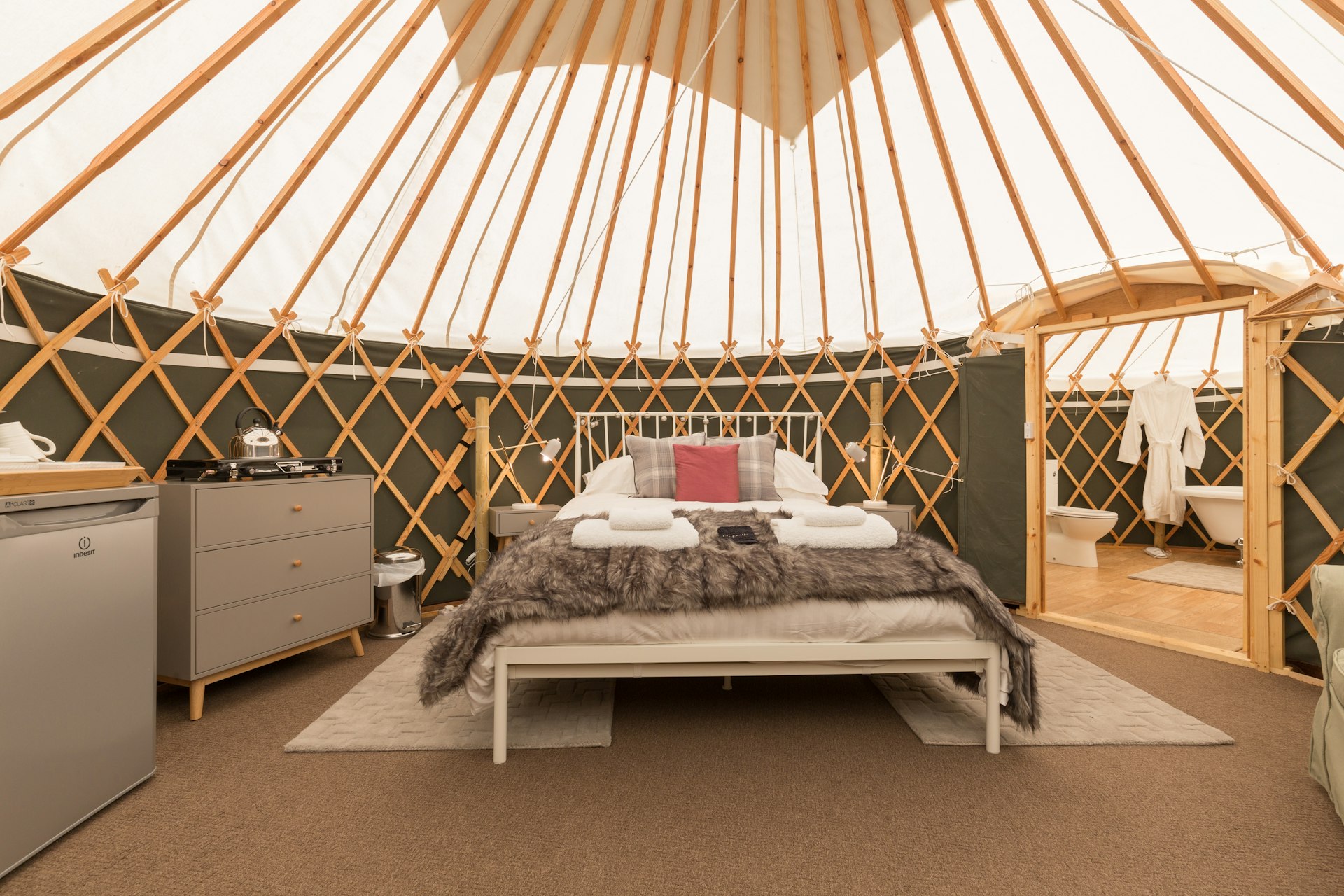Interior shot of a large double bed in a round room with a white and wood canvas roof