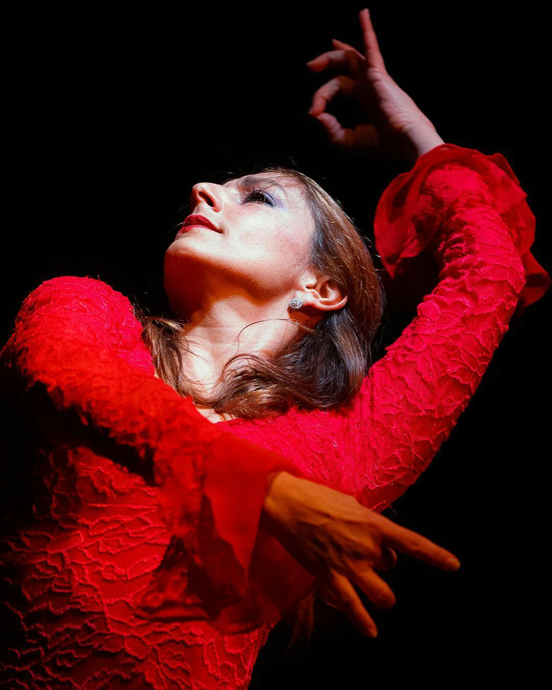 A woman dressed in a red dress strikes a pose during a Flamenco performance