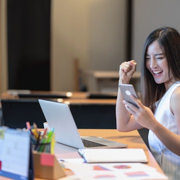 Business and lifestyle concept, Asian businesswoman in casual suit are glad when completed doing online shopping via smart mobile phone application or technology laptop in modern office