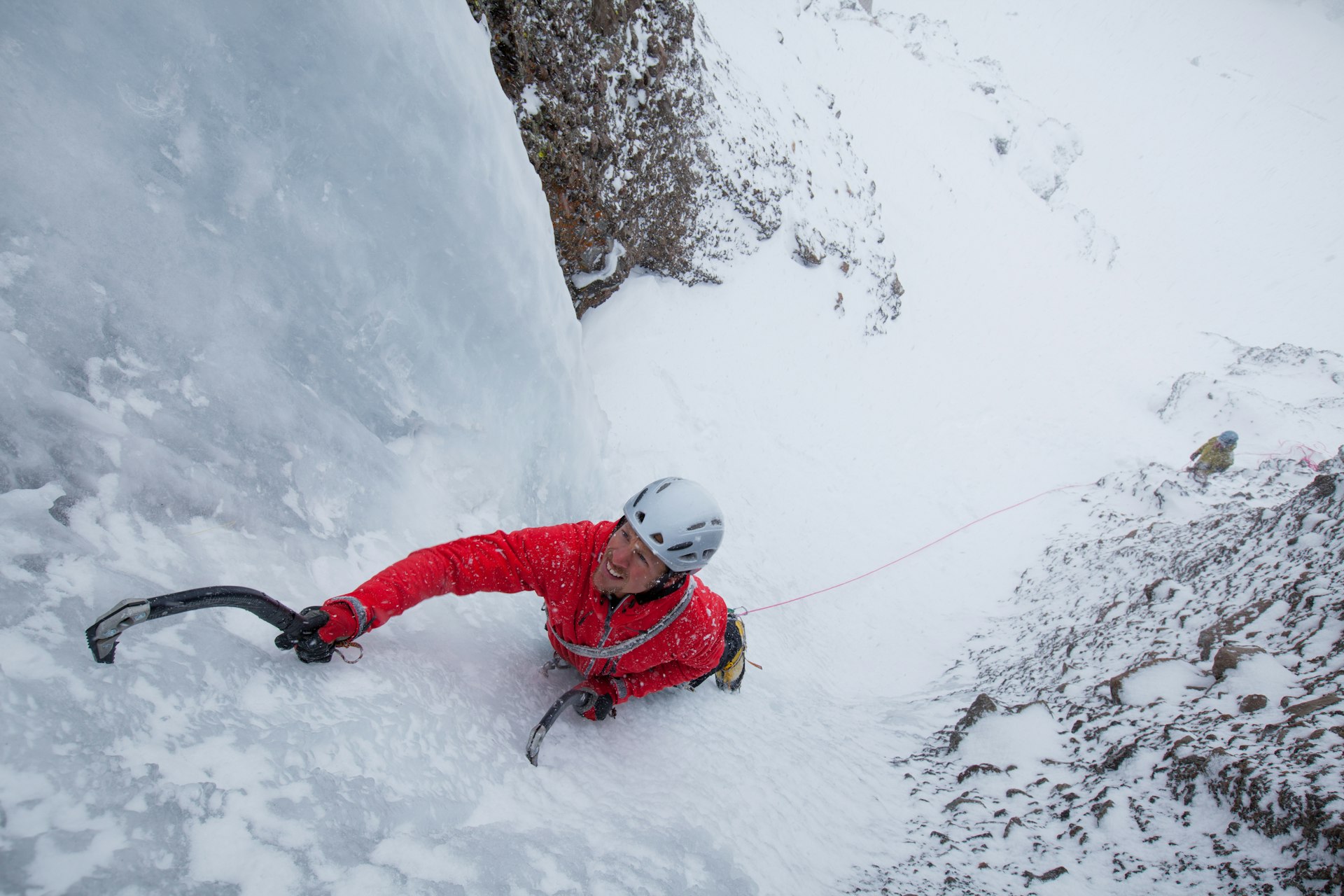 A man wearing a bright red jacket ice climbs in California 