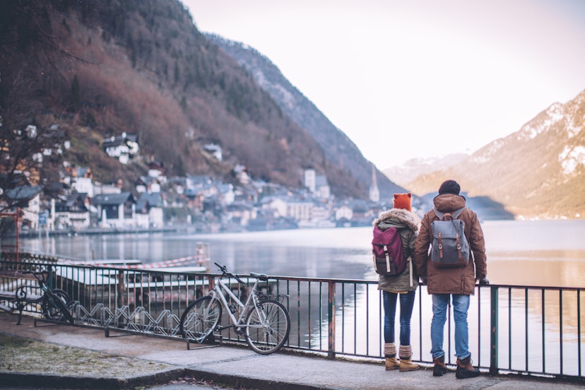 Young couple at winter mountain village, standing on bridge and looking at the Hallstatt lake.