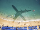Airplane's shadow over a crowded beach at Playa Caleta.