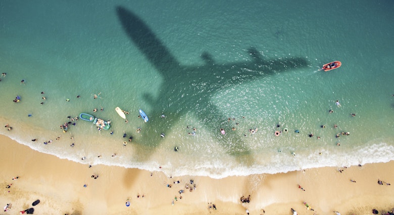Airplane's shadow over a crowded beach at Playa Caleta.