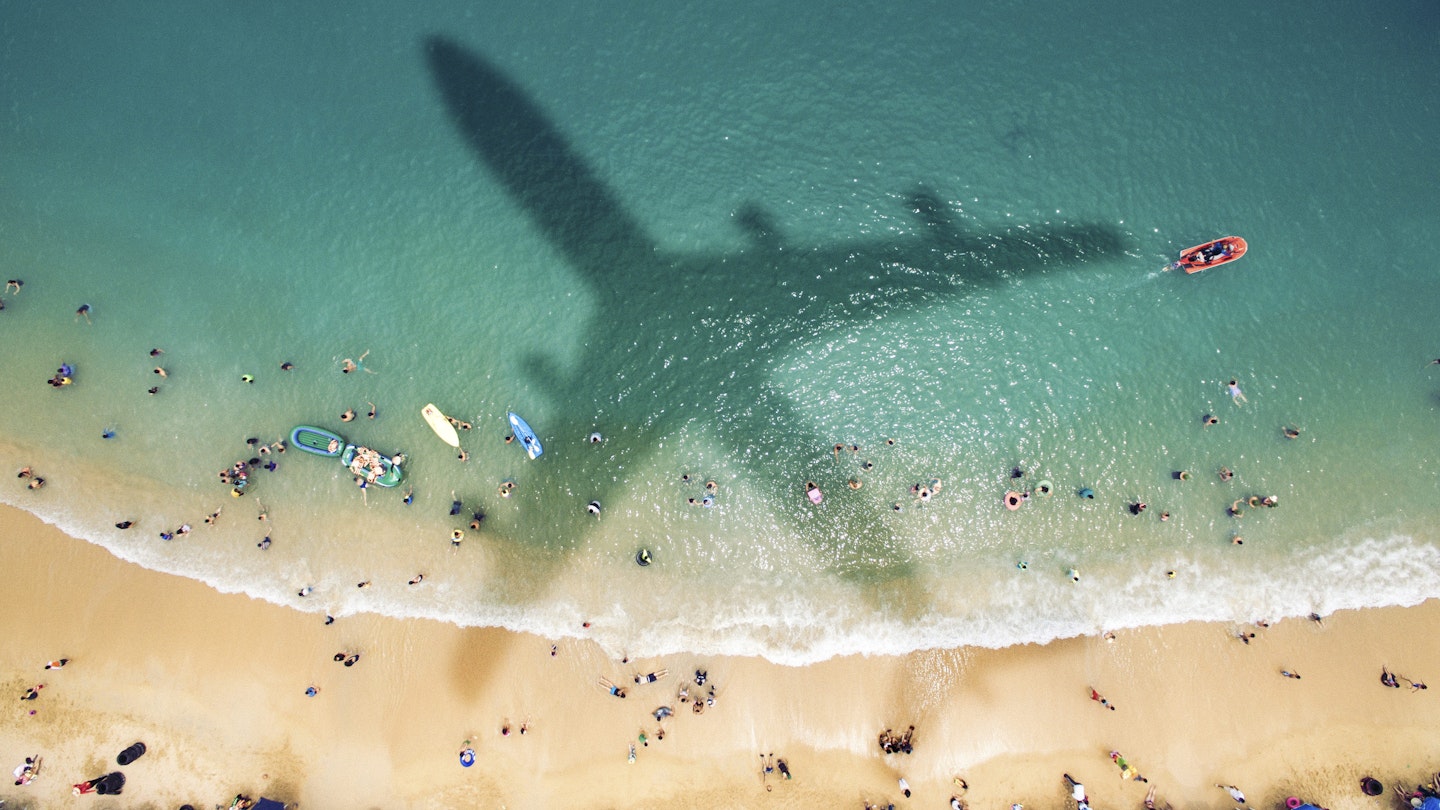Airplane's shadow over a crowded beach at Playa Caleta.