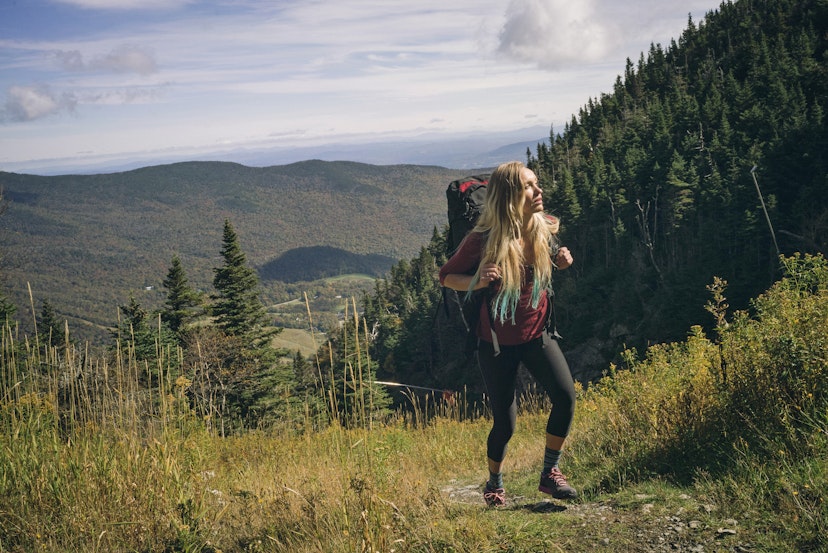 Female hiker walking on a grassy trail at Mount Mansfield.