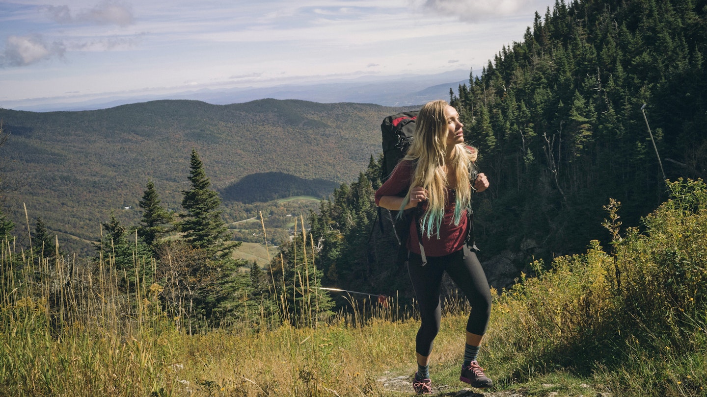 Female hiker walking on a grassy trail at Mount Mansfield.